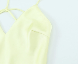 Detail of light yellow satin dress featuring a V-neckline and crisscross back straps