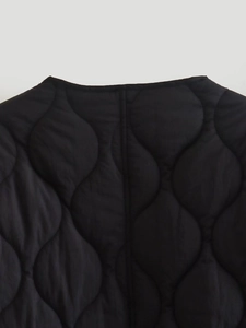 Detail of black onion-quilted jacket showing precise stitching and light synthetic fabric