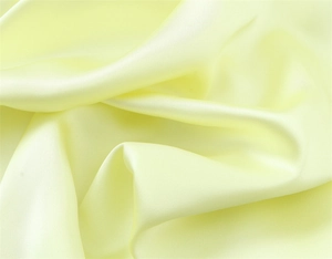 Macro shot showing the smooth satin texture and light yellow silk fabric detail of the dress