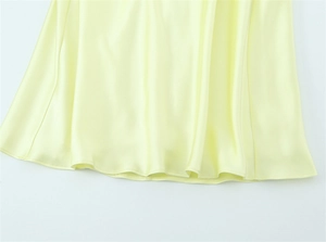 Detail view of the pale yellow satin dress hem showing high-quality smooth fabric texture