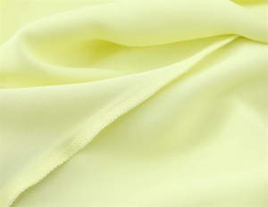 Macro shot of pale yellow satin fabric showing neat inner stitching and soft drape texture