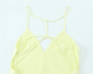 Detail of light yellow satin dress featuring delicate cross-back straps and V-neckline