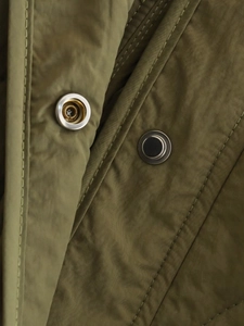 Detail of army green windproof fabric with metallic snap buttons and precision stitching