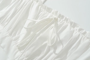Détail de la robe blanche avec volants et tissu en coton avec un nœud délicat