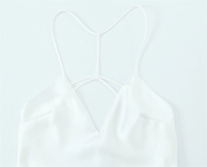 Detail of white satin dress featuring cross-back straps and delicate V-neckline texture