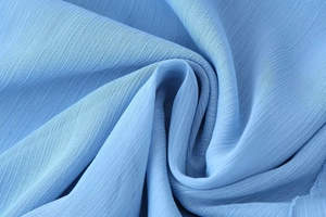 Detail of light blue chiffon fabric with vertical texture and soft draped folds
