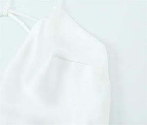 Detail of silk-satin white dress showing fine stitching and delicate shoulder strap texture