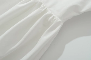 Détail rapproché des fronces et de la texture des coutures sur une robe blanche