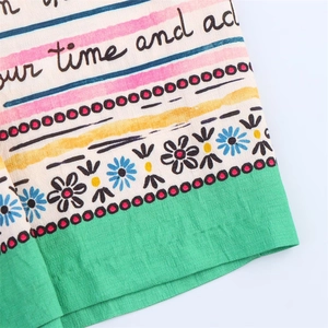 Gros plan d'un tissu imprimé floral avec motifs colorés et détail d'ourlet vert