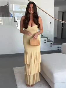 Detail view of a pale yellow sleeveless maxi dress with tiered pleated ruffles and a clutch