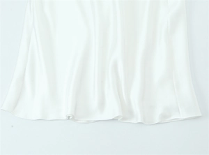 Detailed close-up showing the smooth satin texture and elegant hem of the white dress