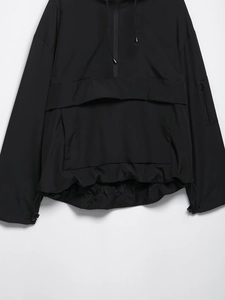 Detail eines schwarzen Windbreakers mit Fronttasche, Halbreißverschluss und Kordelzug