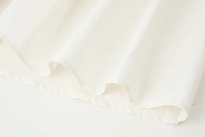 Detailed close-up of the ruffled hem and clean double-needle stitching on white dress