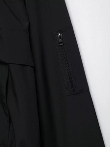 Detail einer schwarzen Outdoor-Jacke mit vertikaler Reißverschlusstasche und Textur