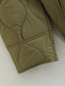 Macro shot of wave quilting detail on olive green padded jacket sleeve