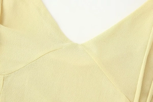 Close-up of a light yellow V-neck knit dress showing fine texture and clean stitching