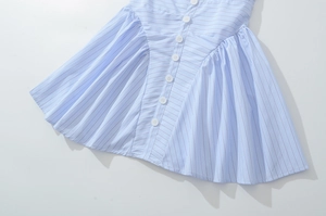 Detail of light blue striped dress with white buttons and delicate pleated waistline