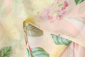 Close-up of floral chiffon fabric showing layered pink petals and green leaf textures