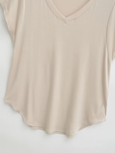 Detail view of beige V-neck T-shirt showing soft knitted texture and curved hemline