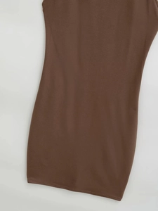 Détail montrant la texture de la robe moulante marron en tissu élastique sur fond blanc