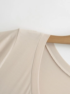 Detail of V-neck knit top in apricot showing premium ribbed texture and neat seams