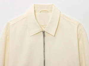 Close-up of cream textured bomber jacket showing silver zipper and collar stitching detail