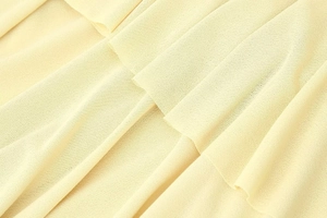 Detailed macro view of light yellow ruffled chiffon fabric with layered textures