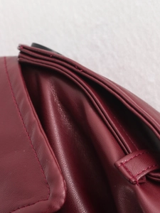 Detail view of burgundy leather handbag showing precise stitching and premium texture