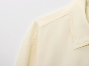 Close-up of cream bomber jacket collar showing twill texture and double stitching
