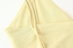 Close-up detail of soft pale yellow knit fabric with delicate thin shoulder straps