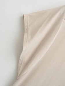 Macro shot of fine stitching on casual V-neck knit top in beige cotton blend fabric