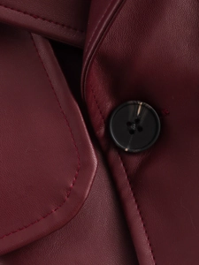 Macro shot of burgundy faux leather jacket detailing with marble button and neat stitching