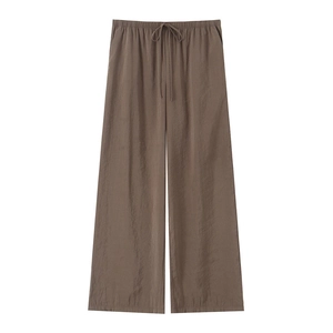 Detailed view of tan wide-leg trousers featuring a drawstring waist and smooth drape
