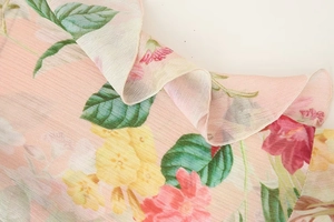 Macro detail of floral print chiffon fabric with delicate ruffled layers and texture