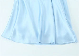 Detail of light blue satin midi dress showing smooth silk texture and neat hemline stitching