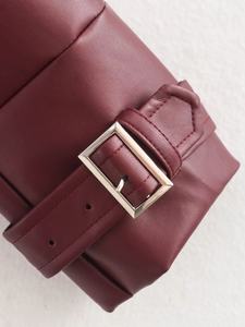 Detail shot of burgundy leather jacket sleeve featuring silver buckle and precise stitching