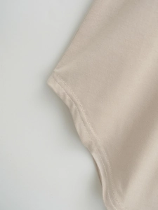 Detailed close-up showing double-needle stitching on beige knitted shirt hemline