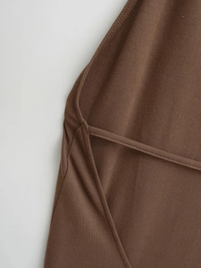 Vue macro d'un tissu en maille marron montrant les coutures et l'ourlet de qualité
