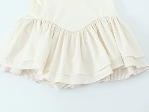 Détail de l'ourlet à volants superposés avec doublure rayée sur robe crème