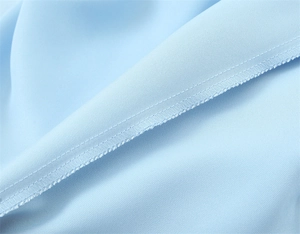 Detail shot of light blue satin fabric with double-needle stitching and raw edge finish
