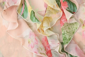 Detailed view of ruffled collar on a floral chiffon blouse with soft pink abstract print