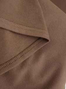 Gros plan d'une robe en tricot marron montrant la double surpiqûre et les détails de couture