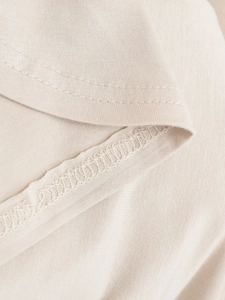 Detail shot of V-neckline with double-needle stitching on beige knit short sleeve top