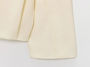Close-up of double-stitched seams on beige bomber jacket showing high-quality fabric texture