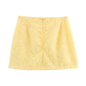Détail d'une mini-jupe jaune clair en tissu texturé à franges avec fermeture éclair invisible
