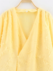 Détail d'un haut jaune à col en V avec texture à franges et tissu translucide