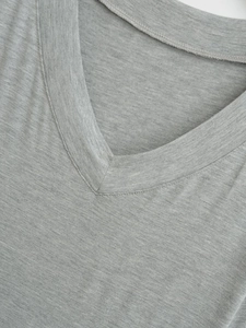 Close-up of the V-neckline on this minimalist grey short-sleeve top showing knit texture