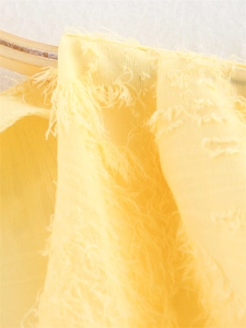 Vue macro d'un tissu jaune doux avec des détails élégants de glands et de franges 3D