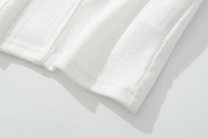 Détail du tissu en maille blanche avec rayures verticales et motifs de broderie anglaise