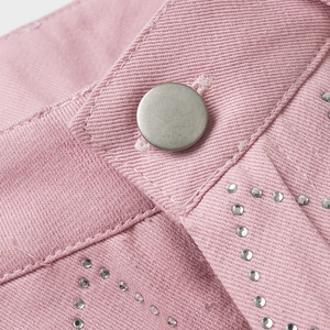 Gros plan d'un pantalon rose à strass avec bouton en métal mat et coutures détaillées